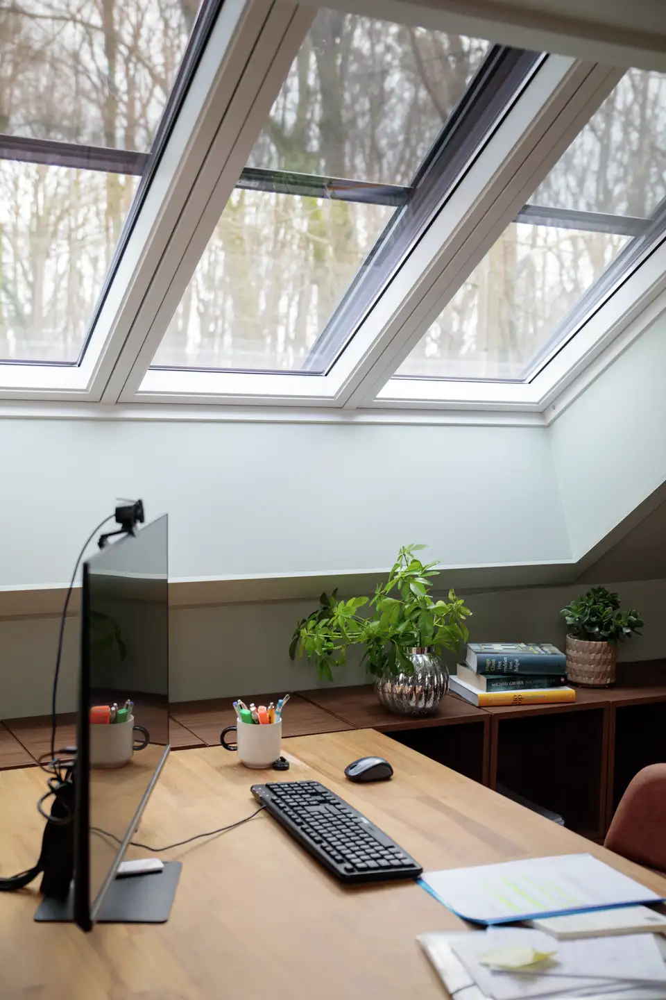 VELUX buitenste zonneschermen temperen het licht en de reflecties in een zolderwerkruimte.