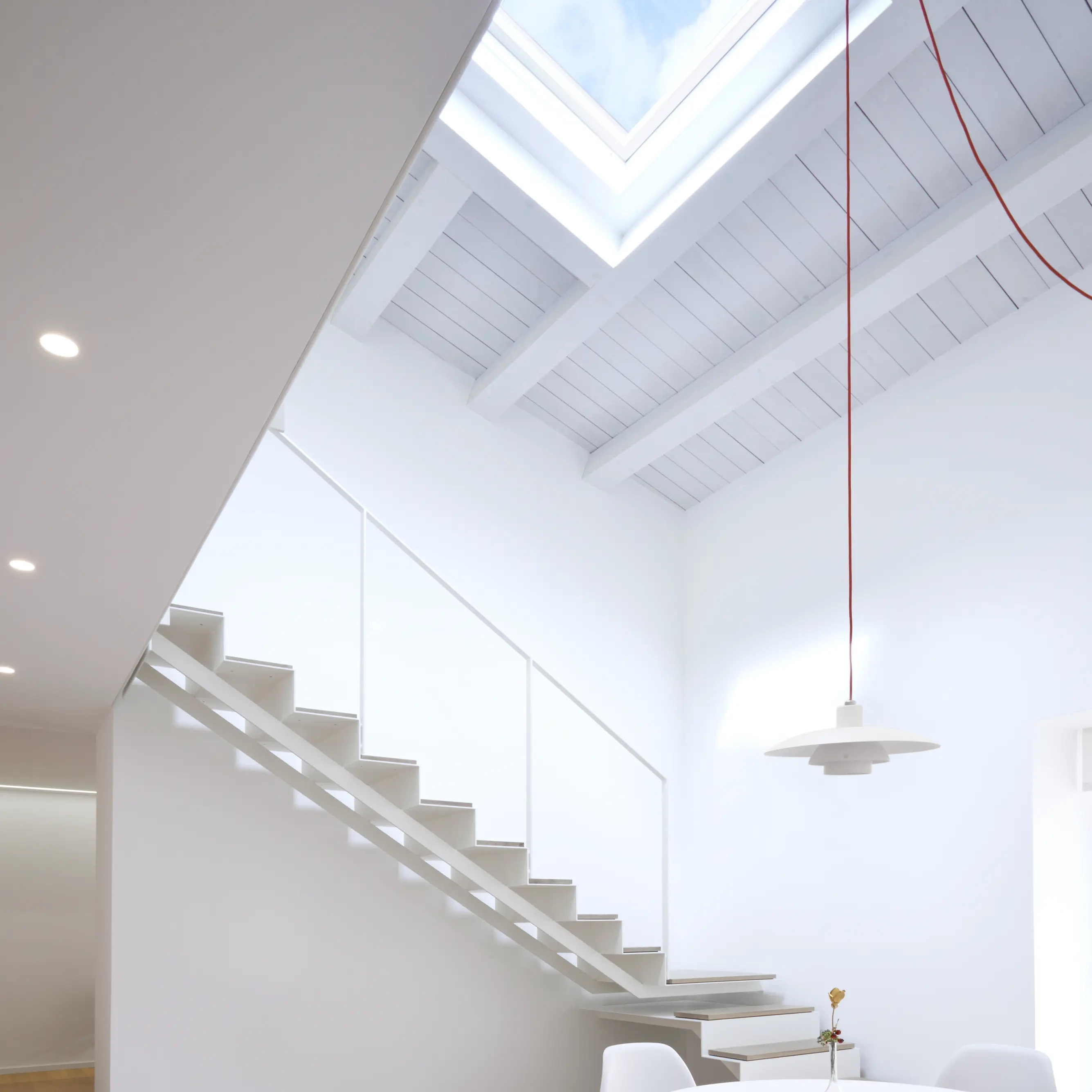 Dining area with round table, chairs, and VELUX roof window.