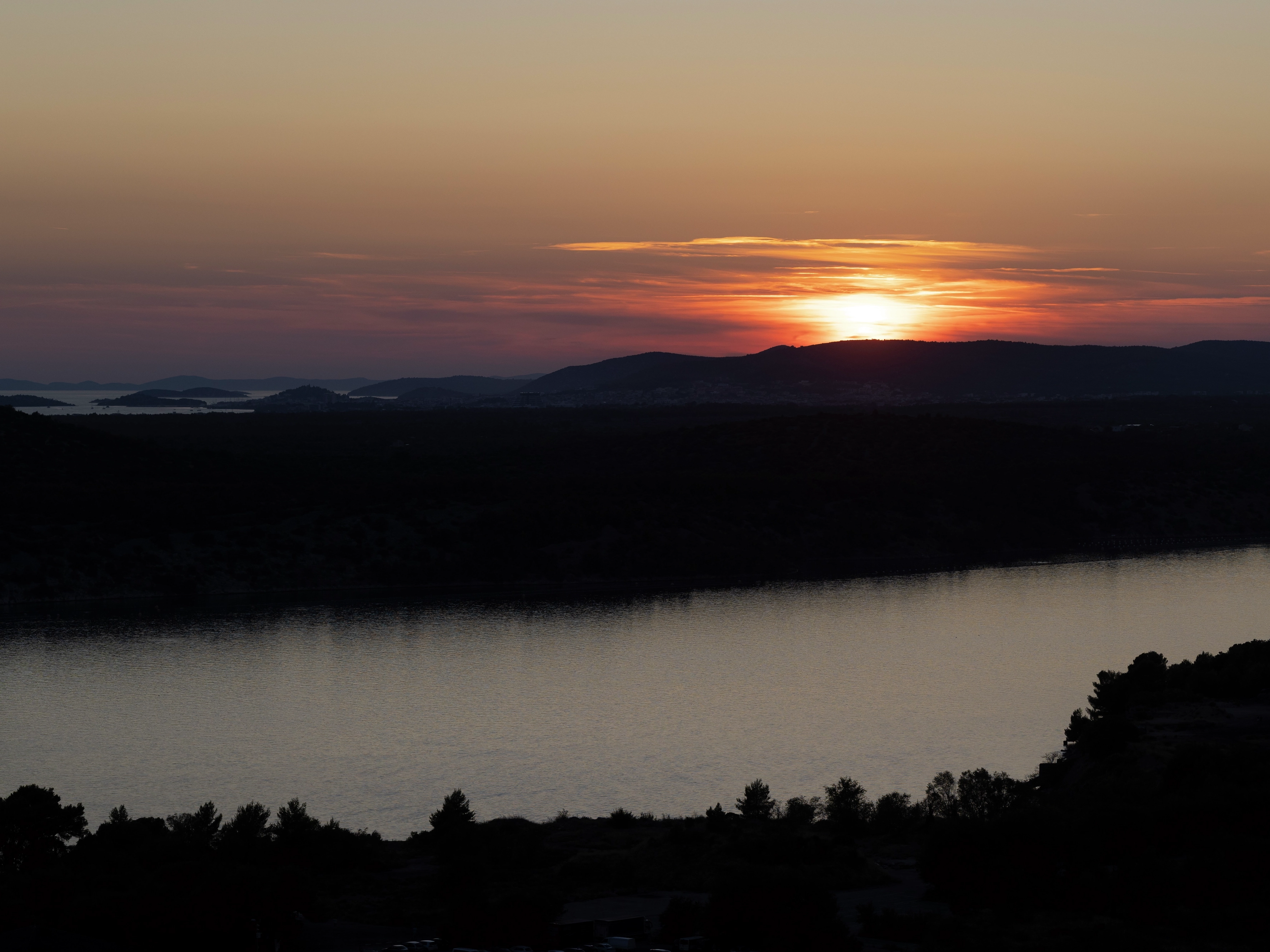 Sunset over water with orange and pink sky.