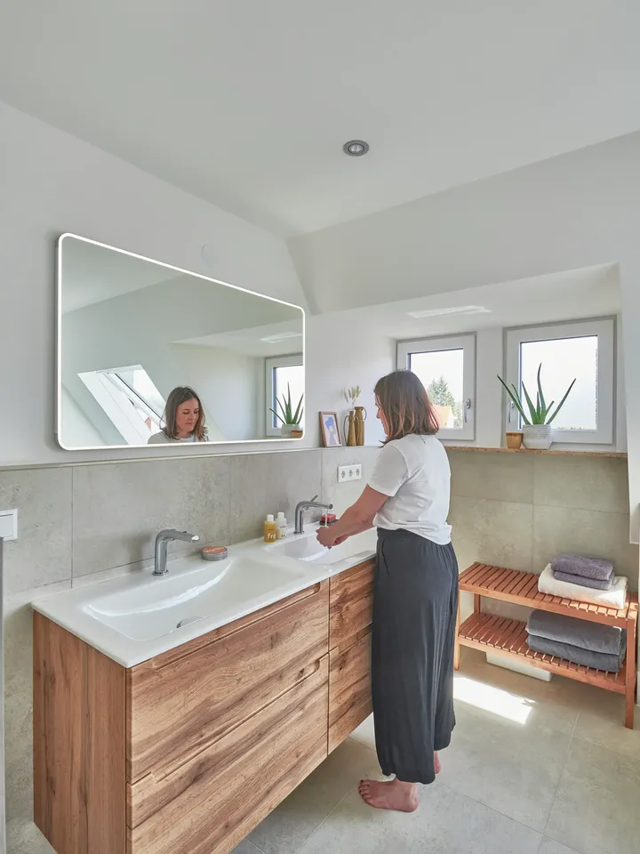 Helles, modernes Badezimmer mit hölzernem Waschtisch, VELUX Dachflächenfenster und grünen Pflanzen.