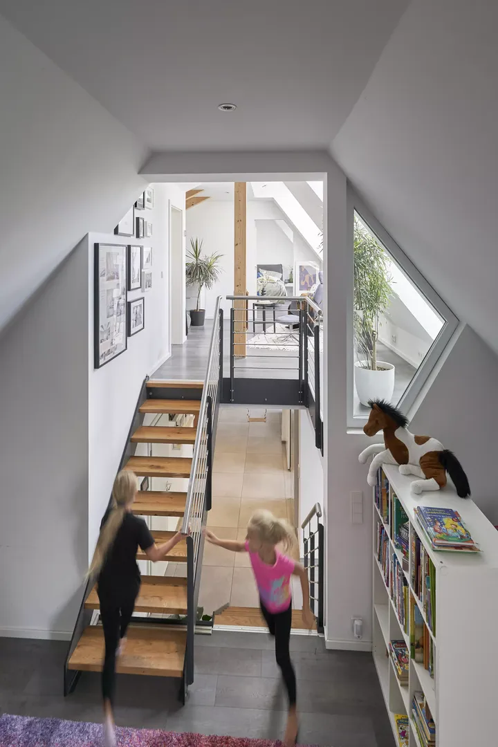 Helles Stiegenhaus mit VELUX-Fenster, spielenden Kindern und einer gemütlichen Leseecke.