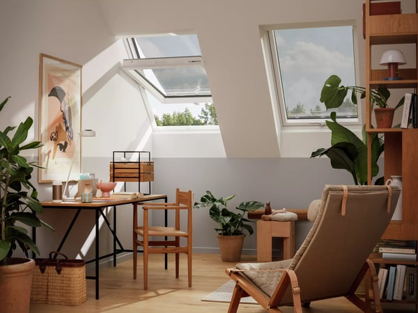 Attic workspace with sloped ceiling and VELUX roof windows, natural light.