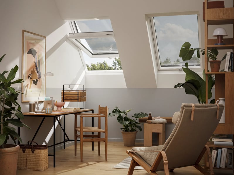 Attic workspace with sloped ceiling and VELUX roof windows, natural light.