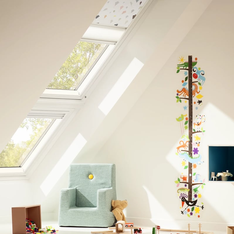 Attic kids room with sloped ceiling and VELUX roof windows, toys and growth chart.