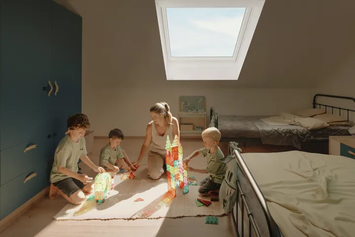 Maminka si hraje s dětmi v podkrovním pokoji se střešním oknem VELUX | VELUX