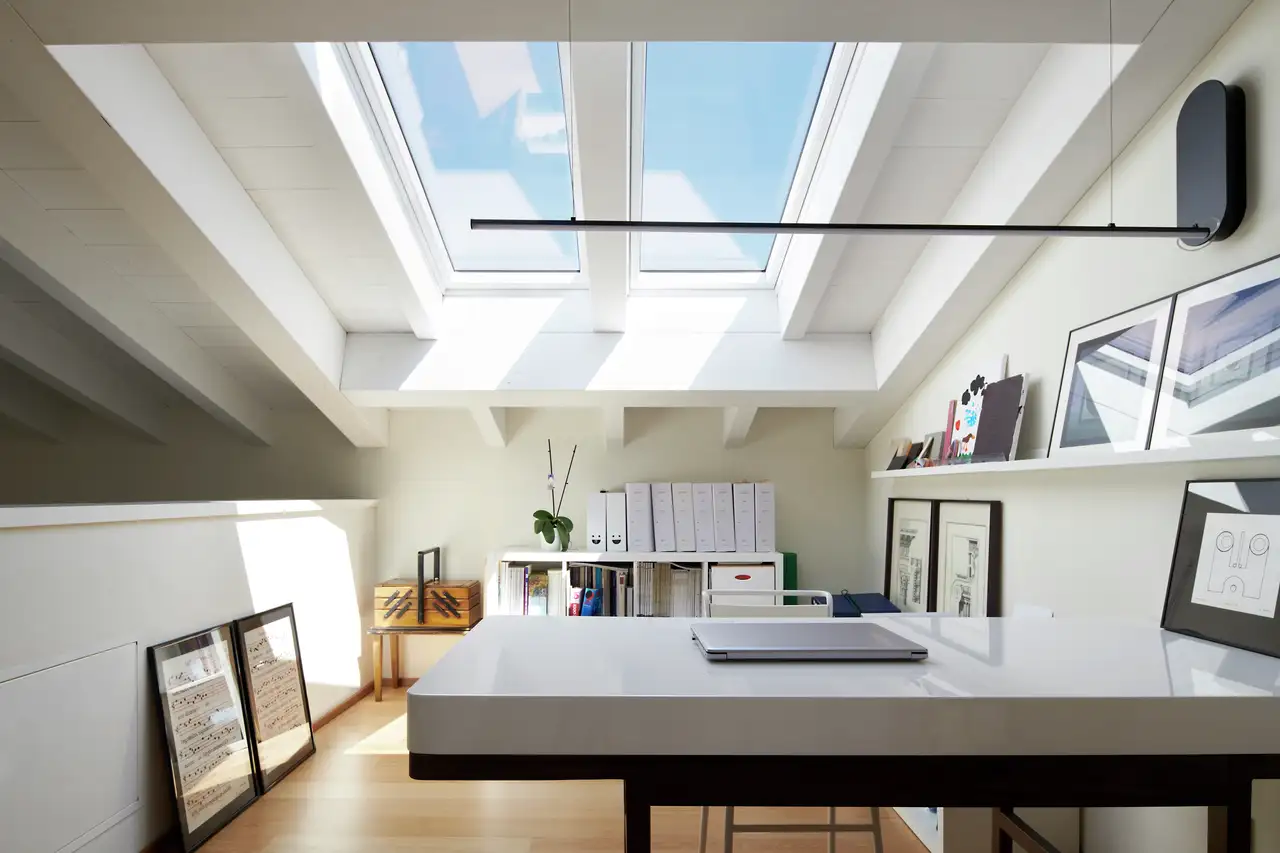 bureau blanc laqué dans un espace de travail sous les combles, baigné de lumière naturelle grâce à une fenêtre de toit VELUX