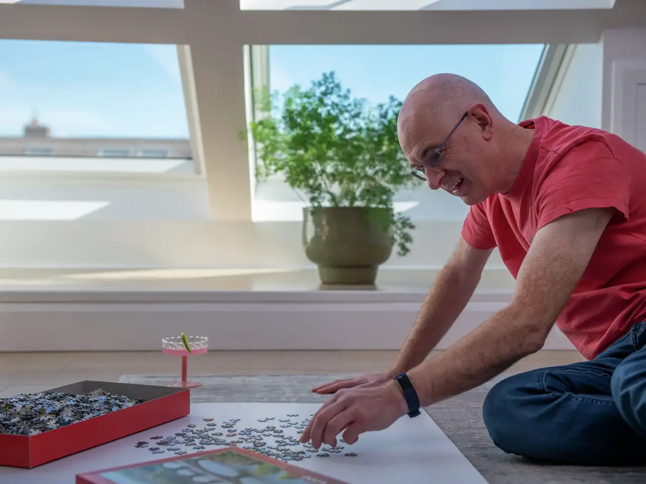 Homme faisant un puzzle au sol près de grandes fenêtres de toit VELUX