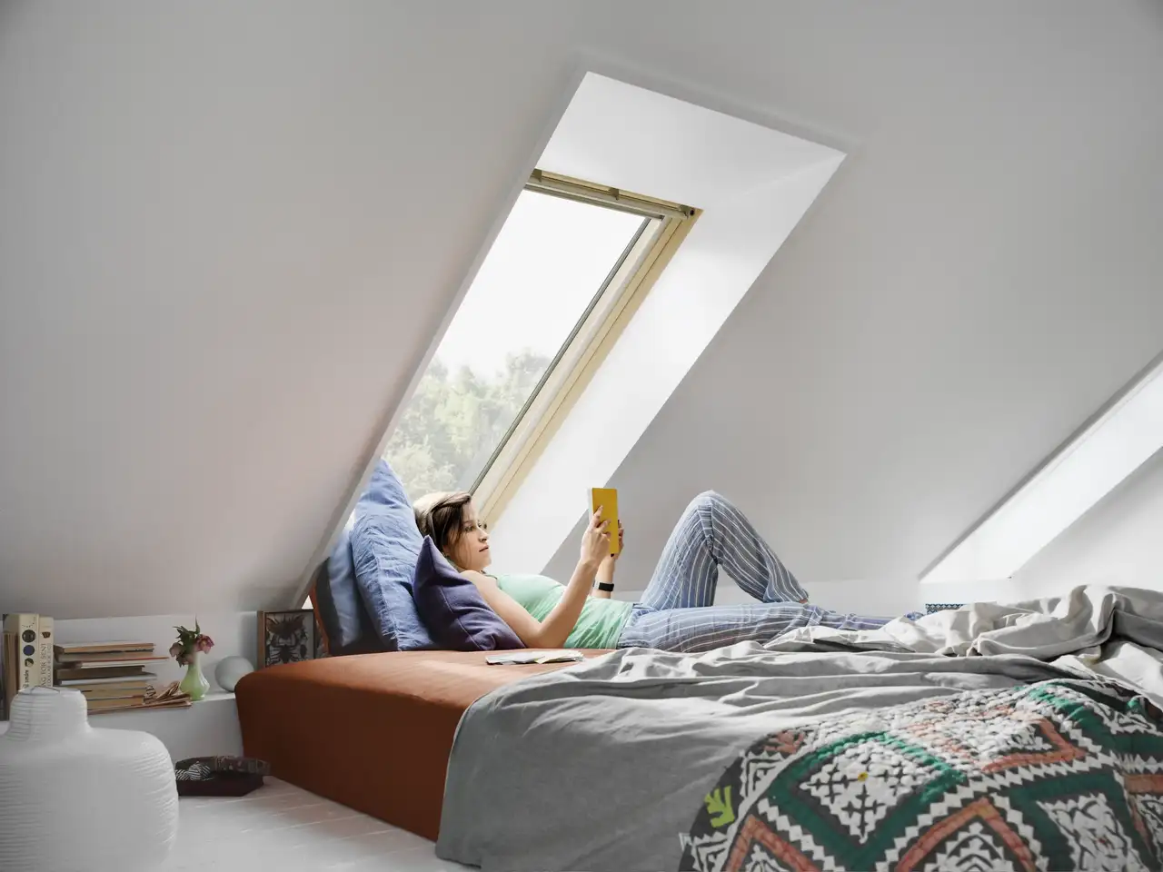 Una donna legge un libro sdraiata sul letto della camera da letto.