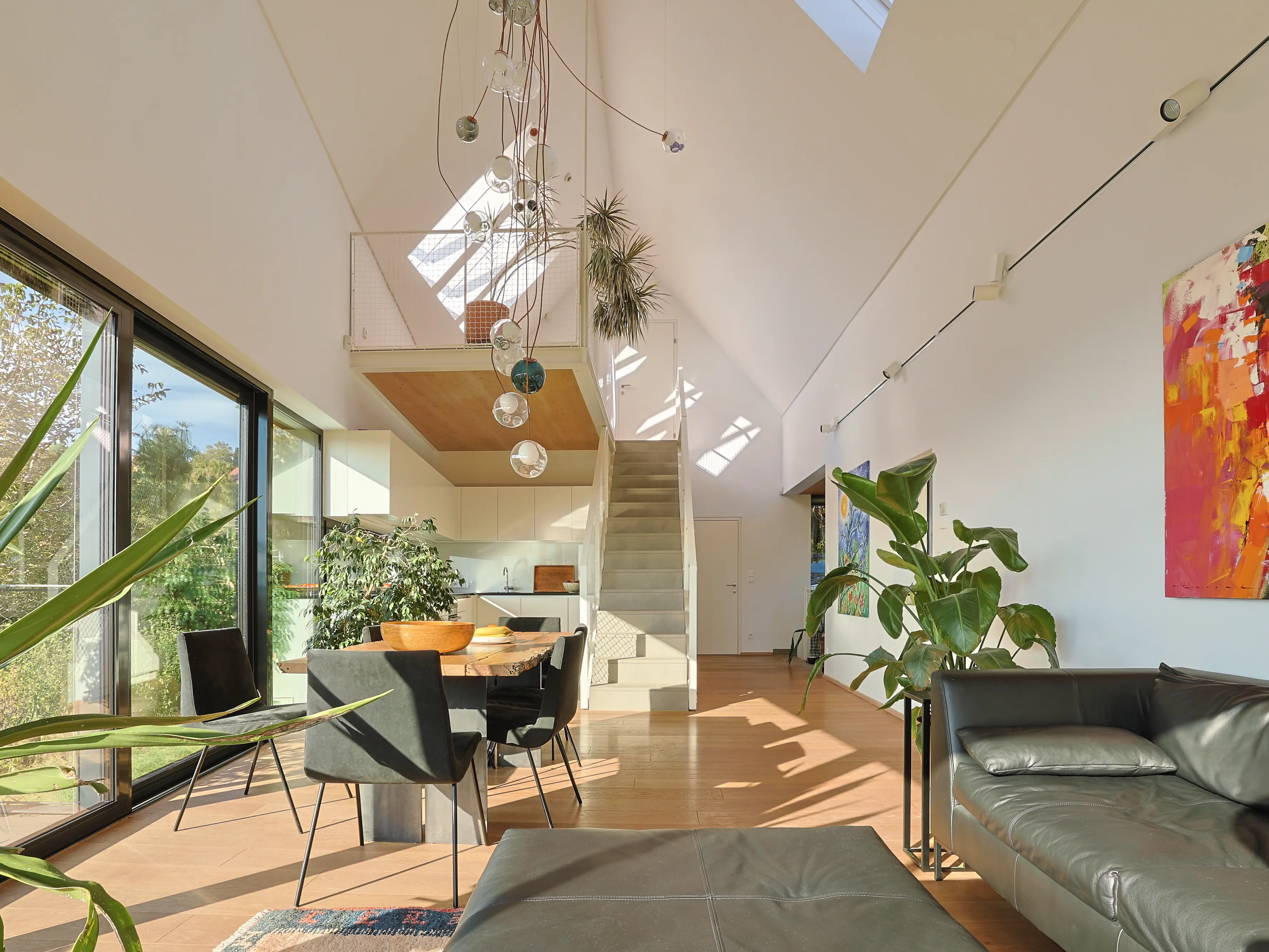 Soggiorno con soffitto a falda, porte finestre verticali e finestre per tetti VELUX, arredamento moderno.