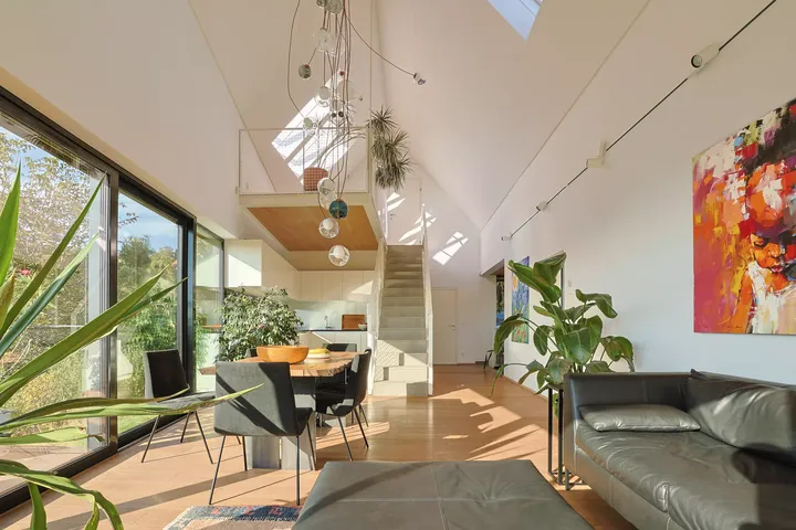 Stilvolles Wohnzimmer mit VELUX Dachflächenfenster, Pflanzen und moderner Treppe.