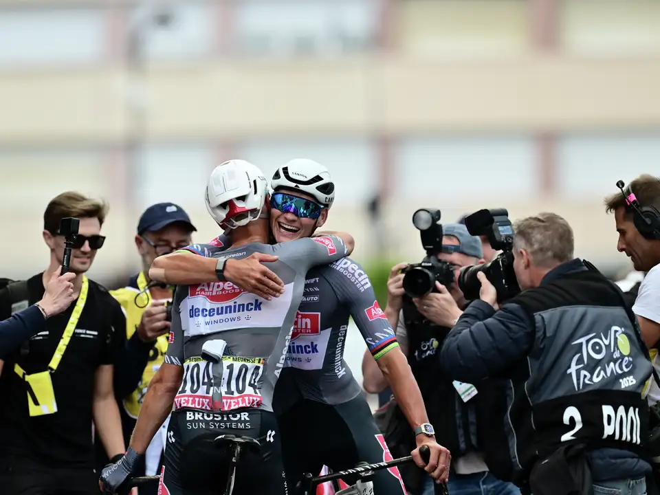 Kolesarji praznujejo, medtem ko fotografi beležijo trenutek med Tour de France 2025.