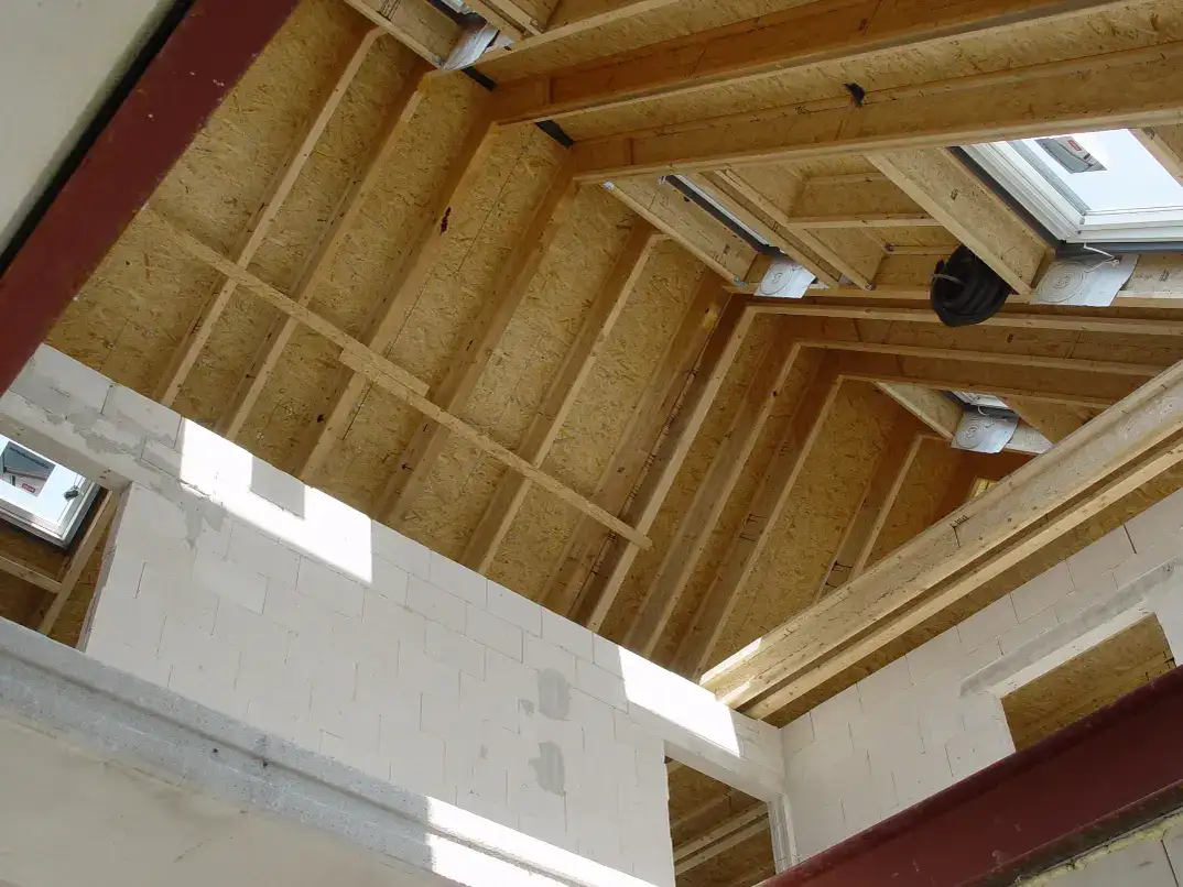 Widok wnętrza poddasza z widoczną konstrukcją dachu oraz oknami dachowymi, które wpuszczają naturalne światło do przestrzeni. | VELUX