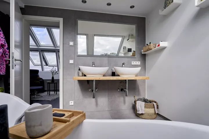 Zeitgemäßes Badezimmer mit zwei Aufsatzwaschbecken und VELUX Dachflächenfenster.