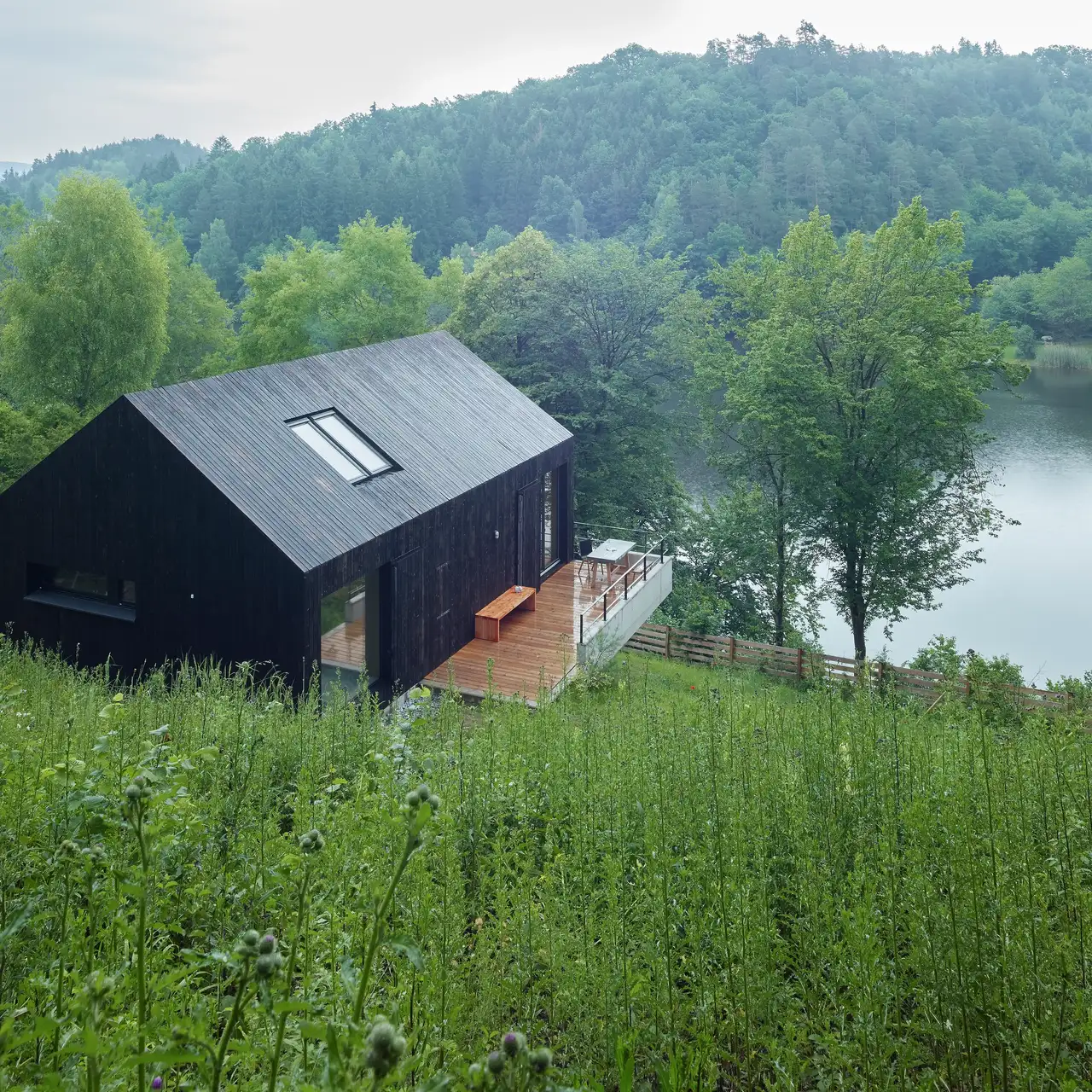 Modernes hölzernes Haus mit VELUX Dachflächenfenster mit Blick auf einen ruhigen See
