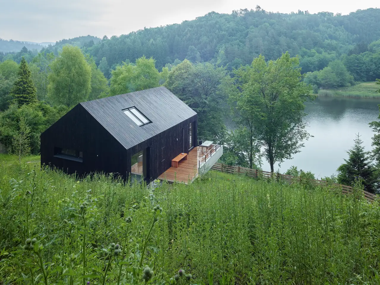 Modernes schwarzes Einfamilienhaus mit VELUX Dachflächenfenster mit Blick auf einen See