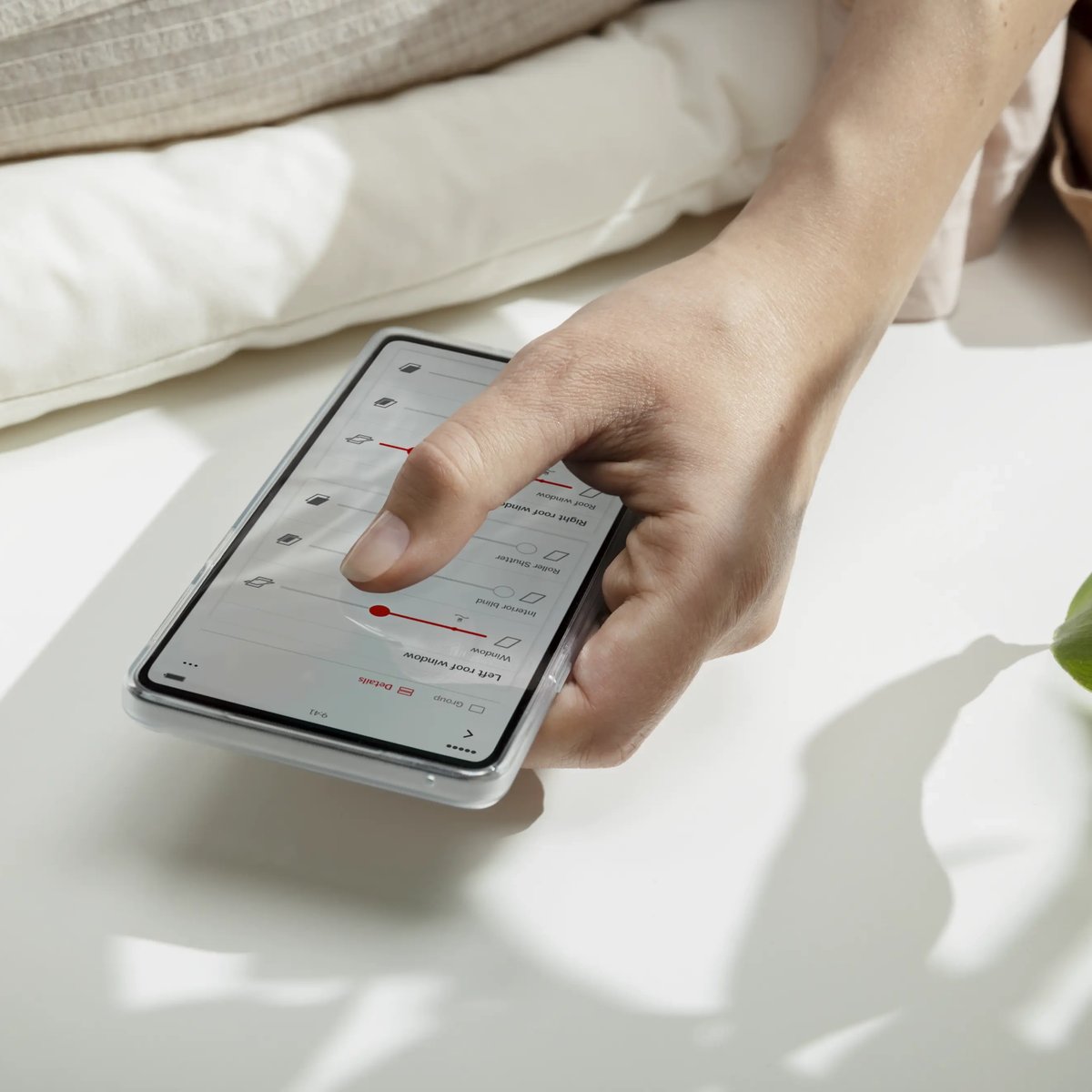 Hand holding smartphone with smart home control app interface.