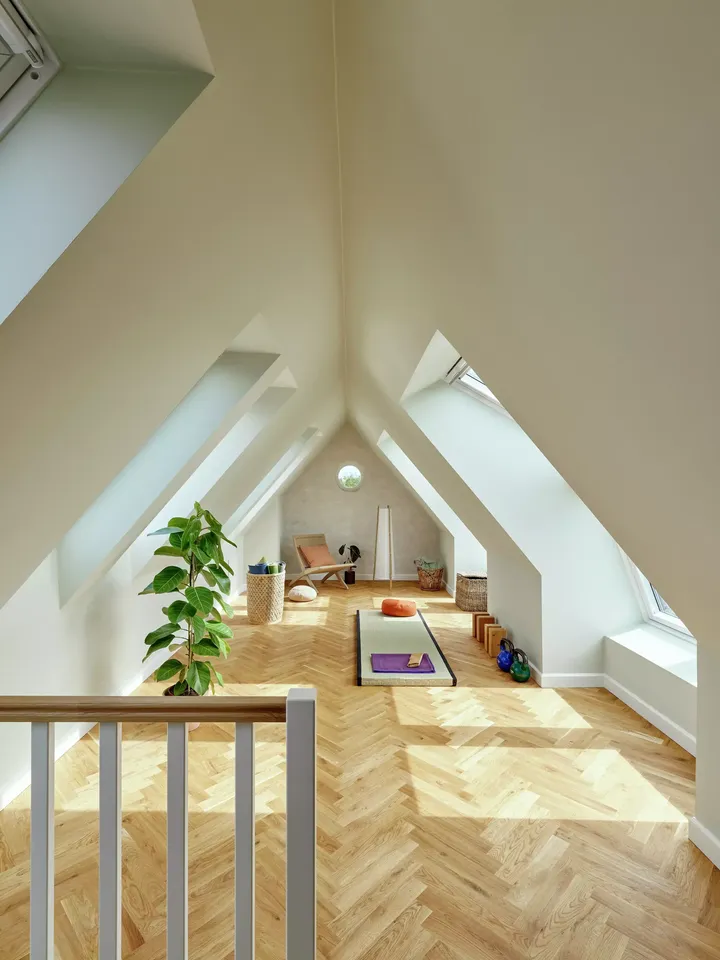 Geräumiges Wohnzimmer im Dachboden mit natürlichem Licht von VELUX Dachflächenfenstern und minimalistischer Einrichtung.