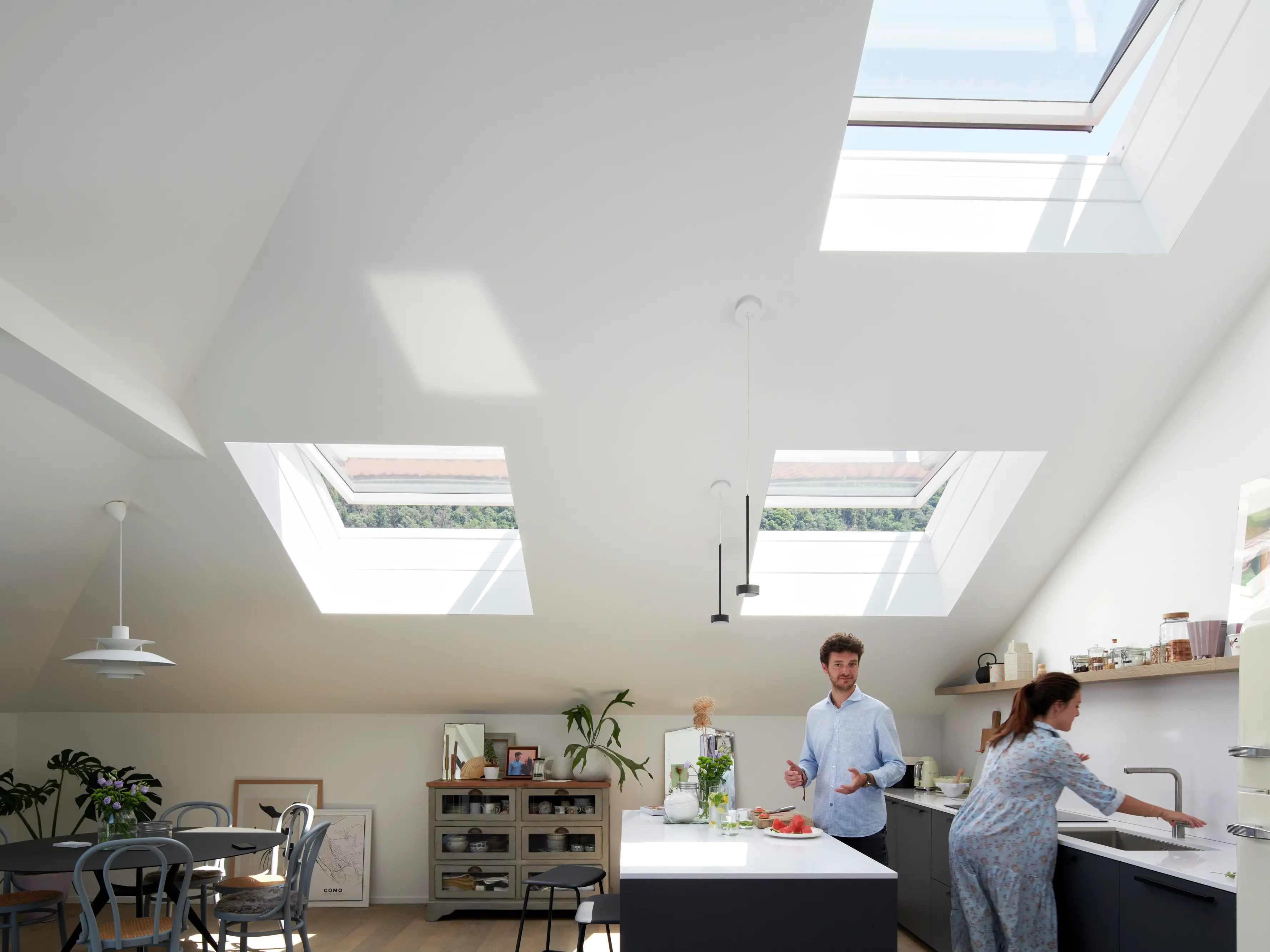 Cuisine moderne avec des comptoirs blancs et des fenêtres de toit VELUX illuminant l'espace.