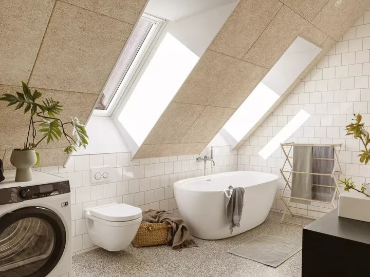 Helles Badezimmer mit freistehender Badewanne, VELUX Dachflächenfenster und modernen Geräten.
