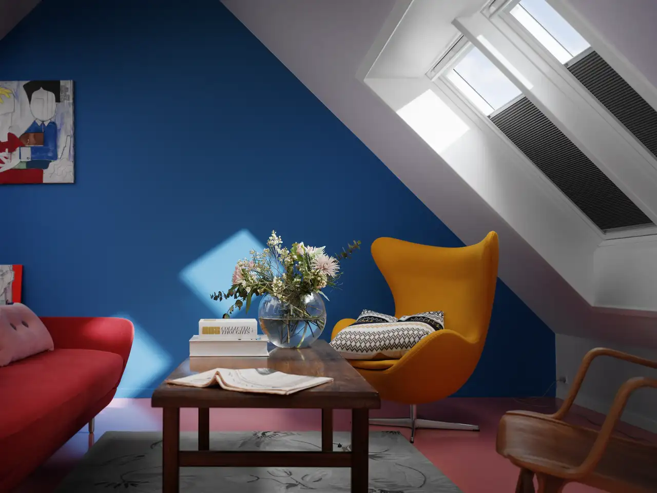 Salon mansardé avec mur bleu, fauteuil jaune, canapé rouge et fenêtres de toit équipées de stores intérieurs. 