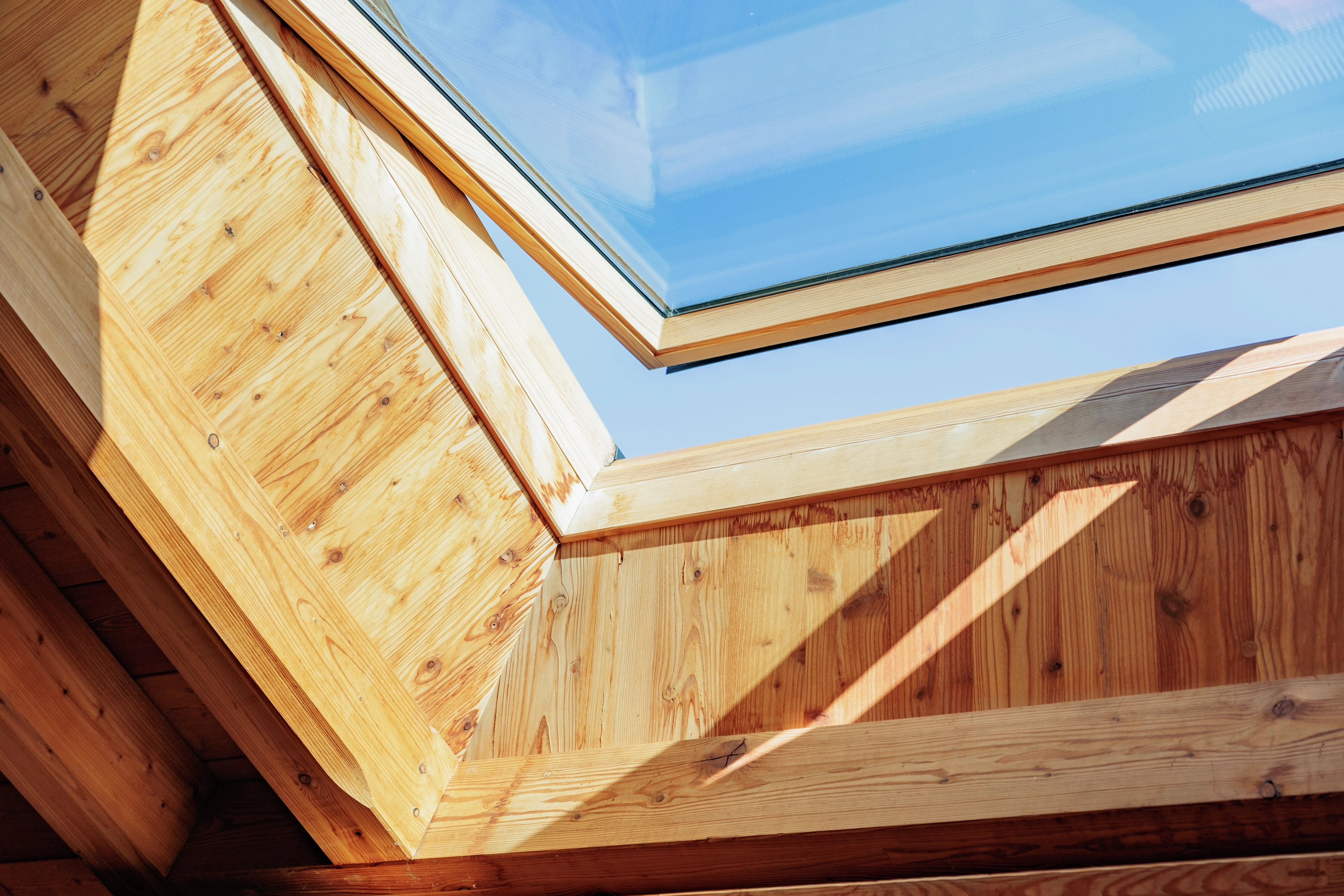 Vue intérieure d'une fenêtre de toit avec triple vitrage, encadrée de bois naturel, conçue pour fournir une isolation thermique et acoustique optimale dans un intérieur lumineux.