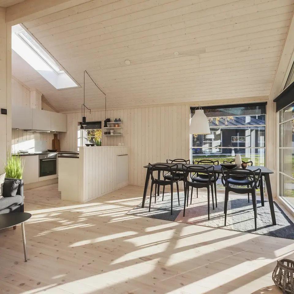 Sommerhus i klitlandskabet med stor terrasse og moderne, sort design, ideelt orienteret til sollys