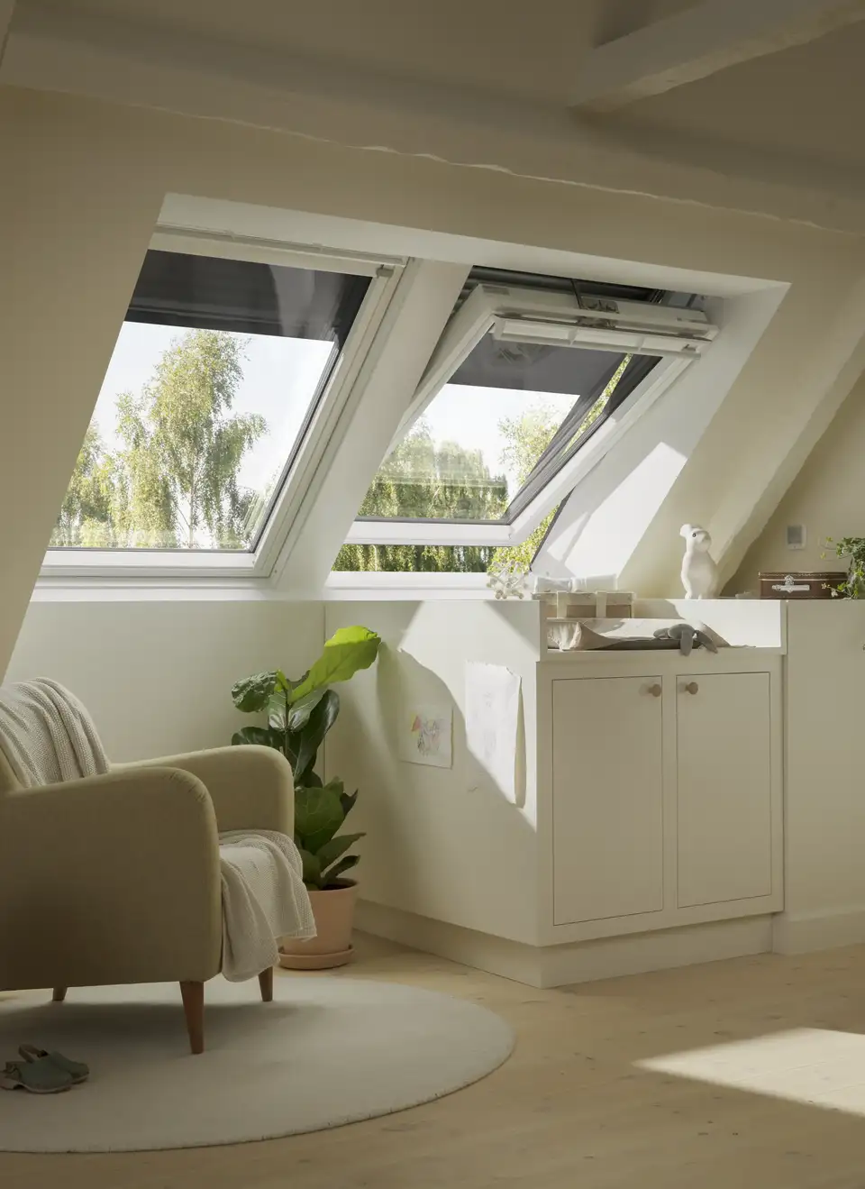 Salón en espacio abuhardillado con ventanas de tejado y persianas VELUX 