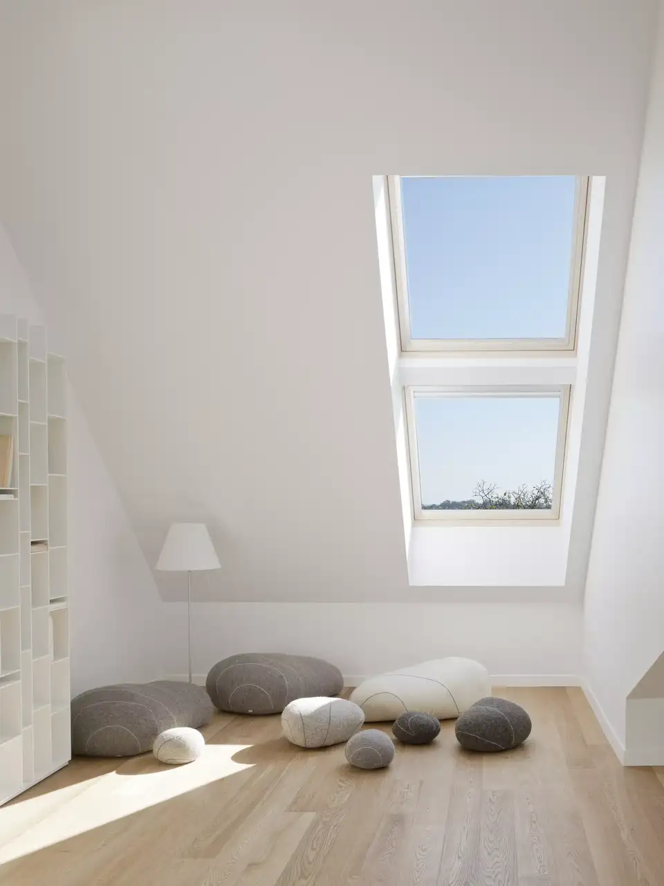 Mezzanine en bois avec canapés design, lampe, bibliothèque et porte-fenêtre VELUX