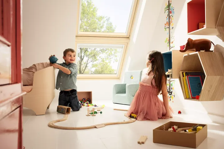 Zwei Geschwister spielen mit einer Holzeisenbahn vor kindersicheren Dachfenstern  | VELUX Magazin