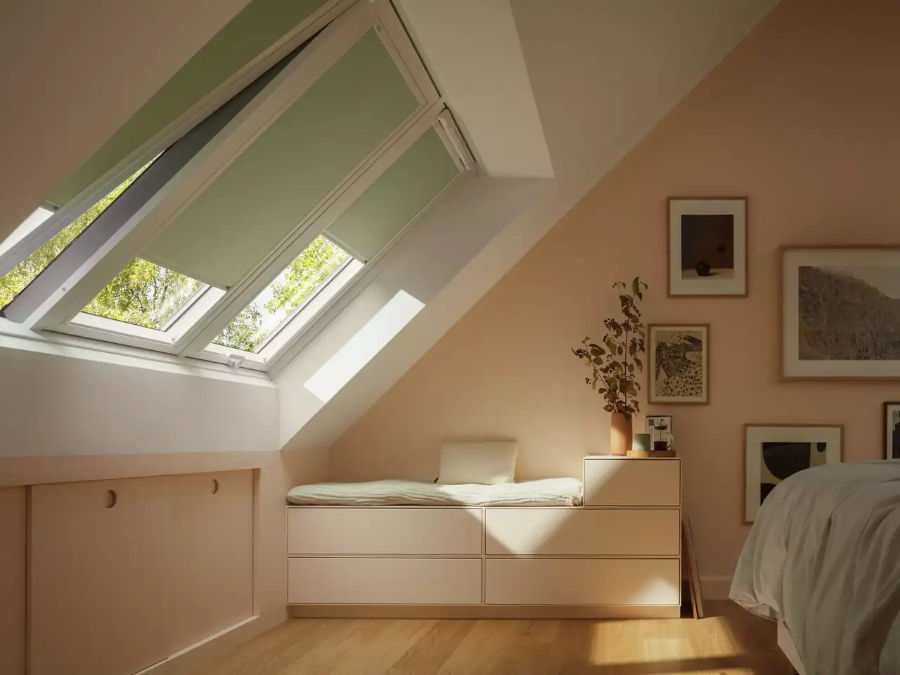 Gemütliches Schlafzimmer im Dachboden mit VELUX Dachflächenfenster und warmer natürlicher Beleuchtung.