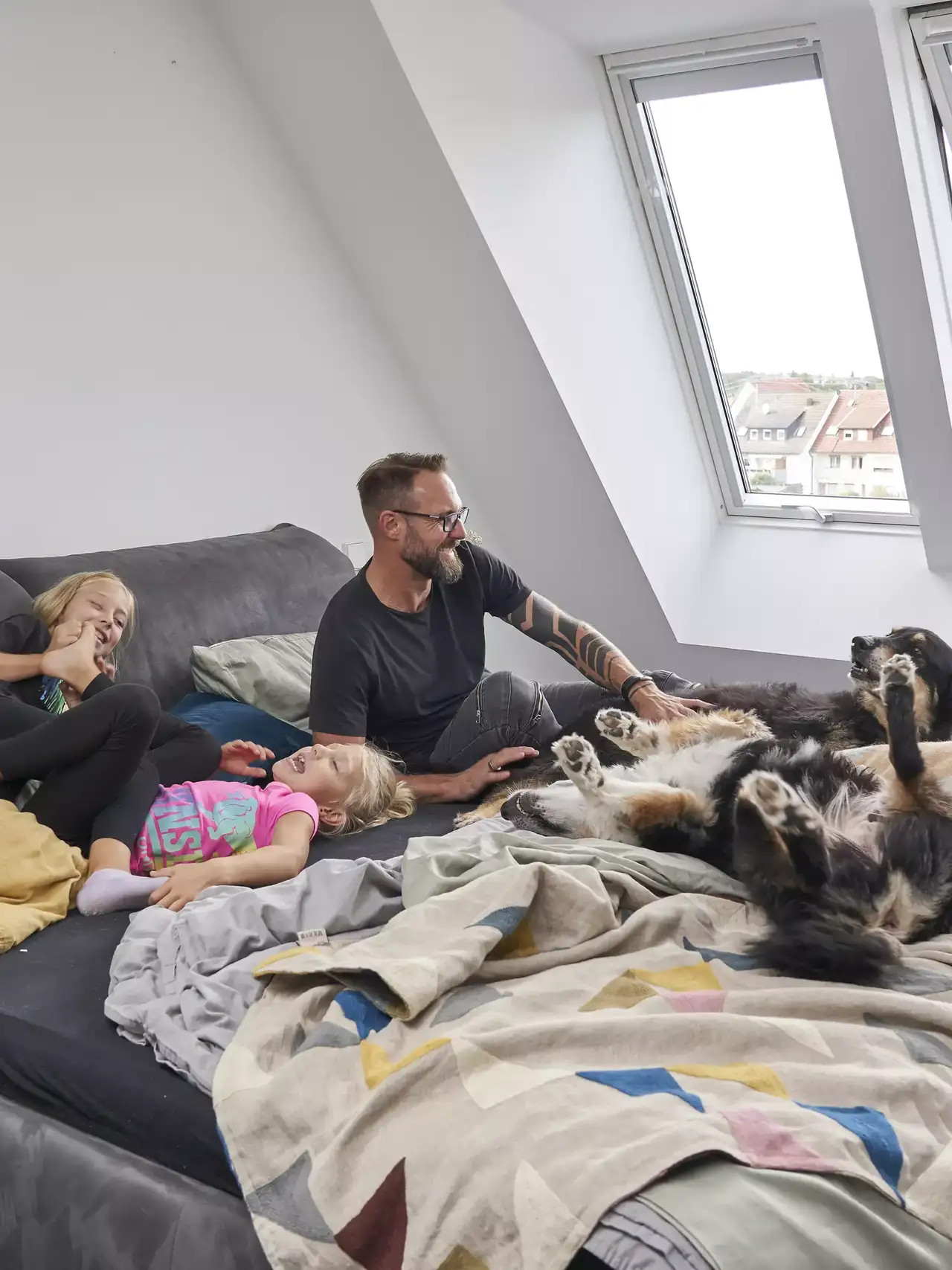 Wohnzimmer im Dachboden mit Familie und Hund unter natürlichem Licht von VELUX Dachflächenfenster.