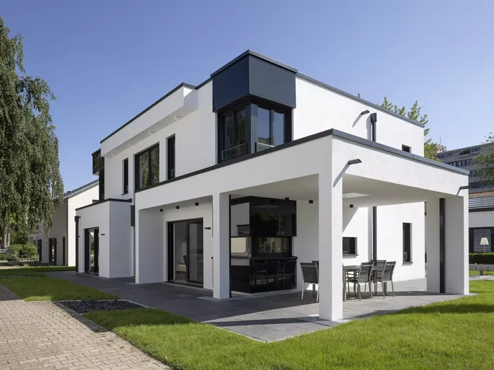Modernes weißes Einfamilienhaus mit schwarzen VELUX Dachflächenfenstern und Essbereich im Freien.
