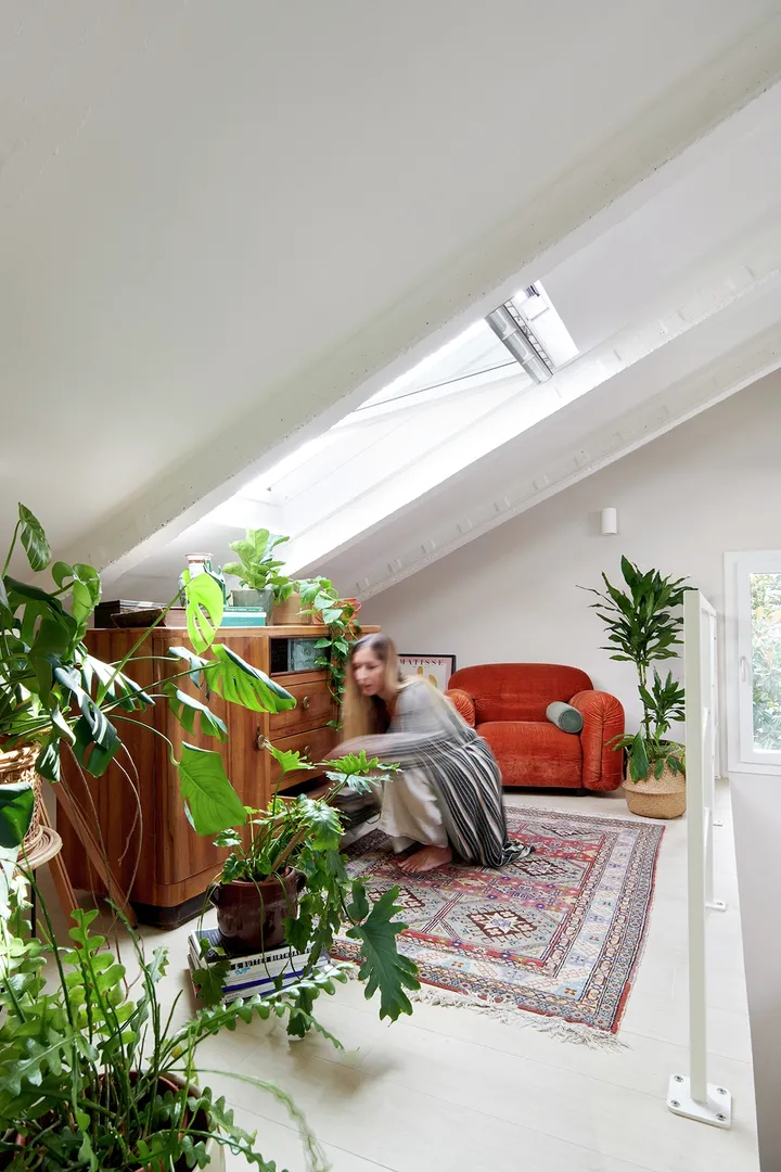 Helles Wohnzimmer im Dachboden mit VELUX-Fenstern, Pflanzen, Vintage-Möbeln und orangefarbenem Sofa.