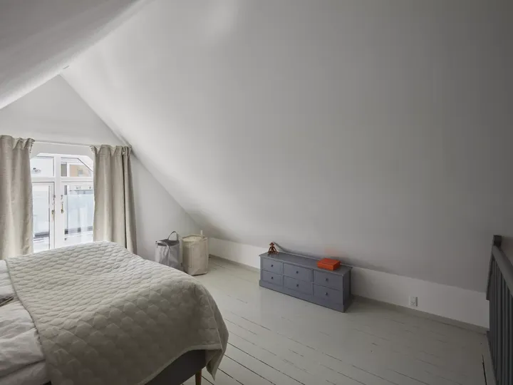 Minimalistisches Schlafzimmer im Dachboden mit natürlichem Licht von VELUX Dachflächenfenster und weißer Dekoration.