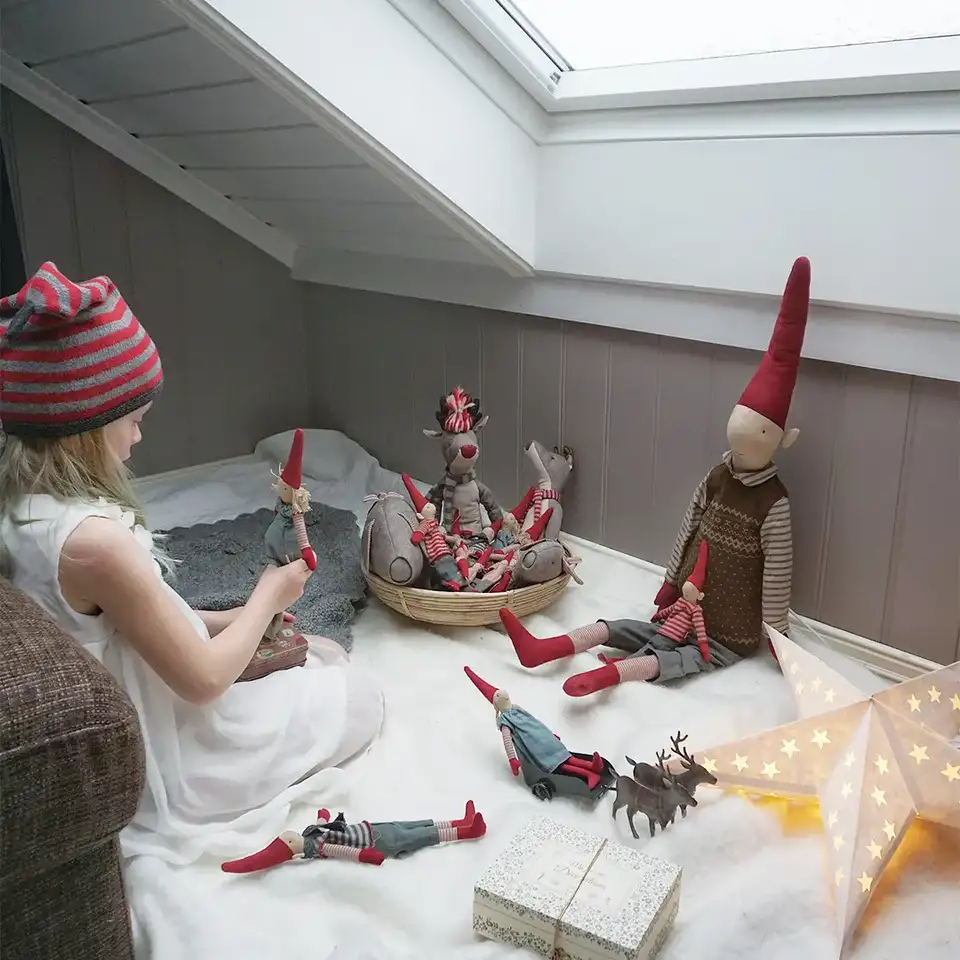 Bambina che gioca con pupazzi decorativi natalizi vicino a una finestra per tetti VELUX.
