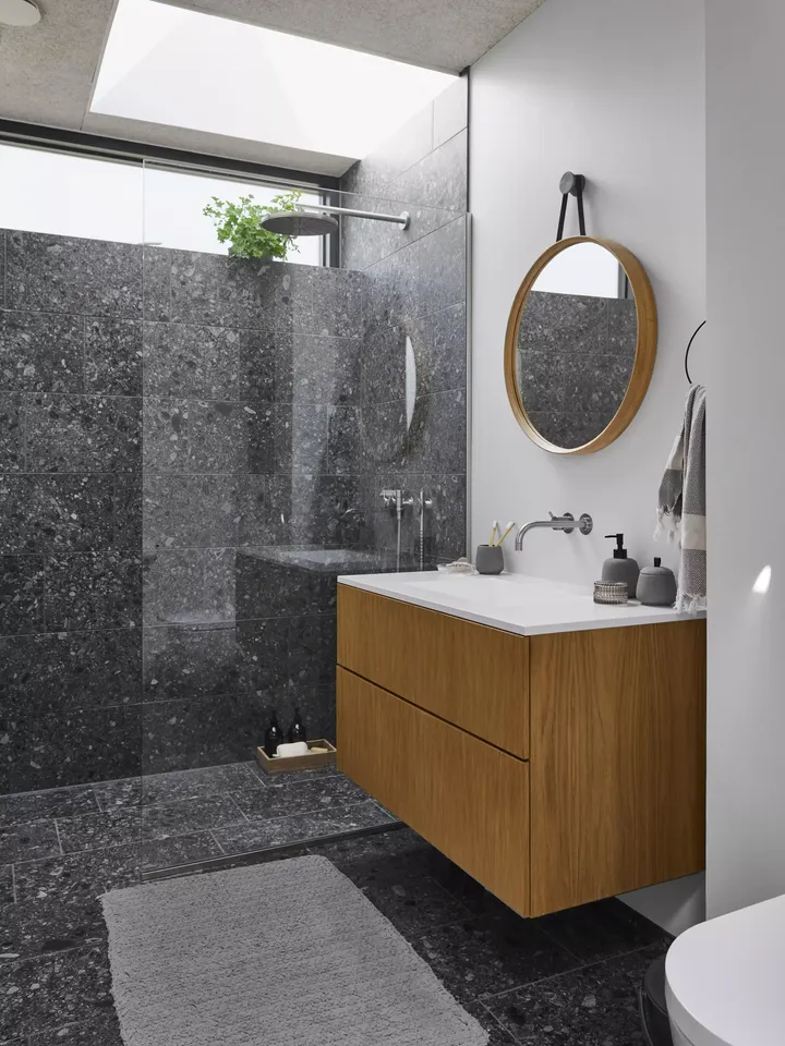 Modernes Badezimmer mit dunklen Marmorfliesen und VELUX Dachflächenfenster, das für natürliches Licht sorgt.