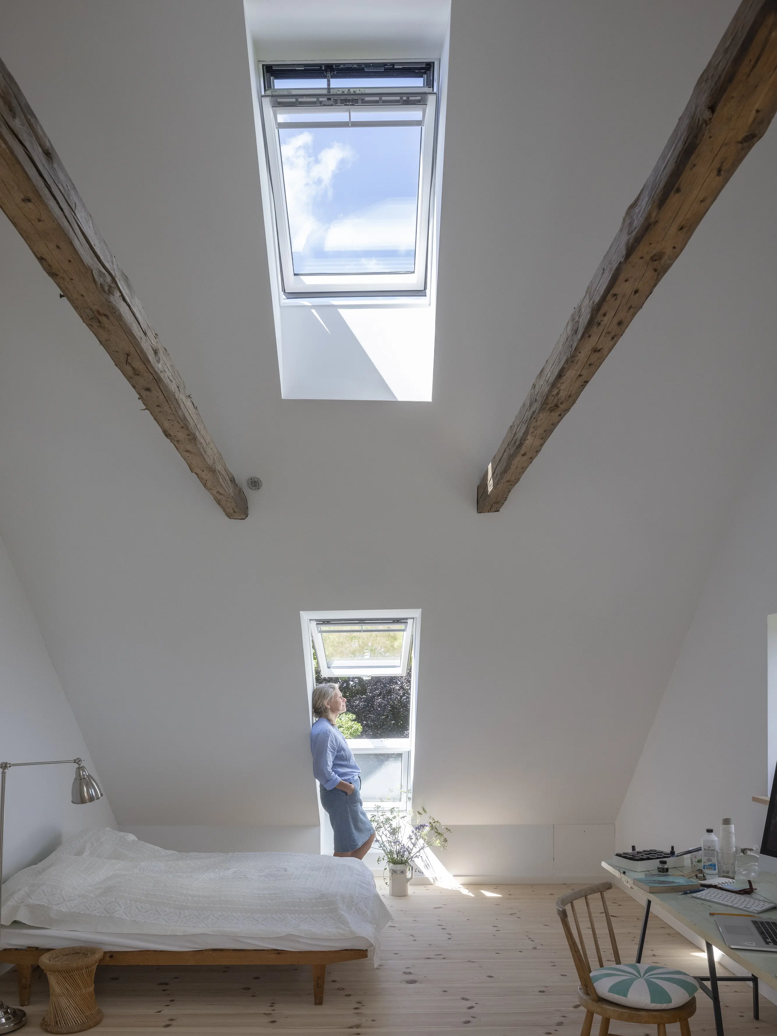 Attic room with sloped ceiling, VELUX windows, and exposed beams.