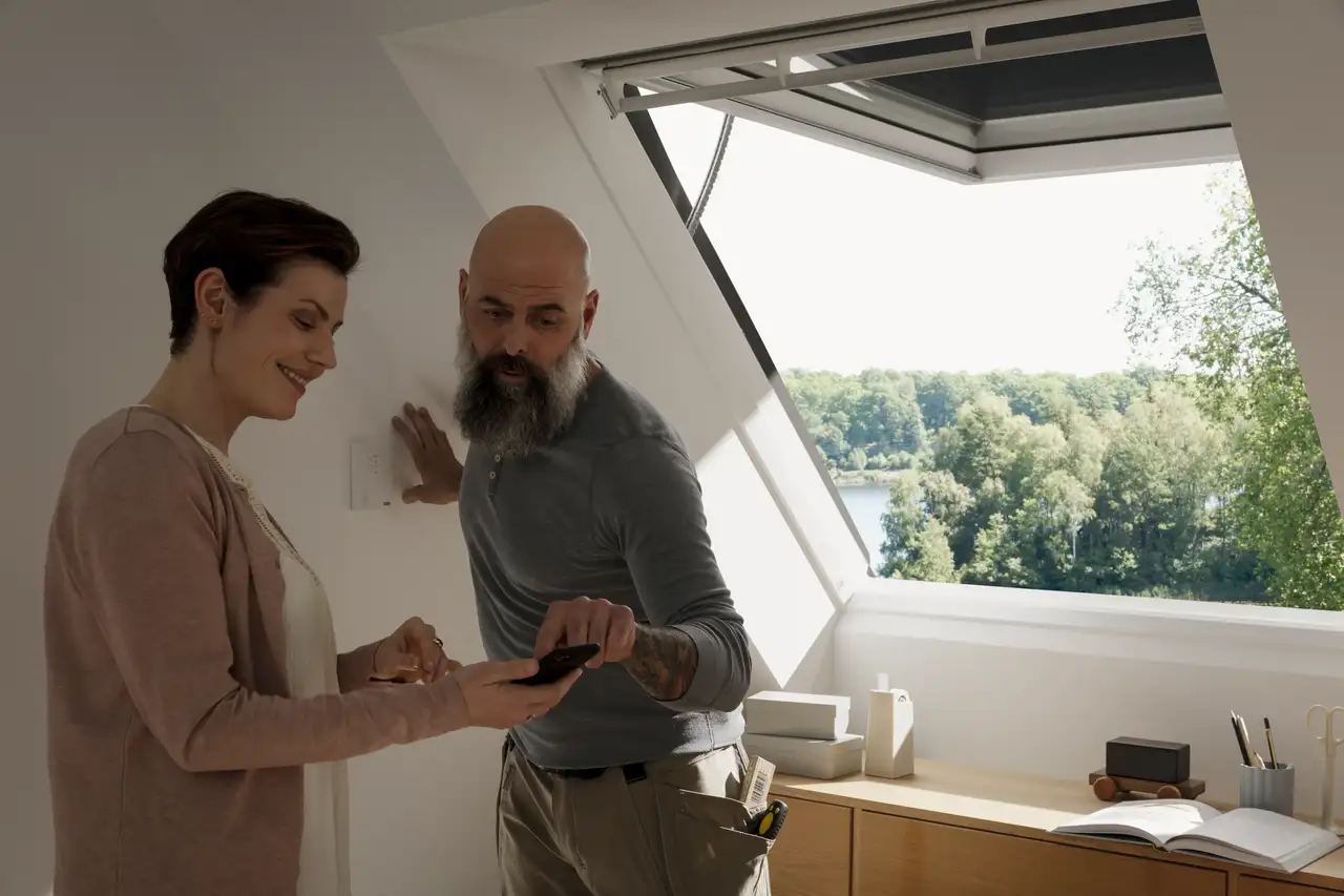 Moteris ir santechnikas kalbasi ir žiūri į planus telefonu