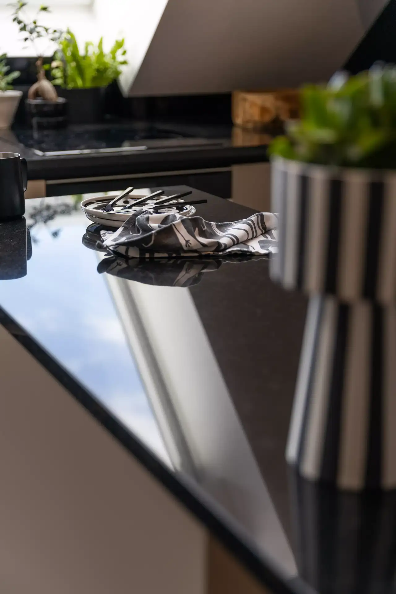 Polierte schwarze Küchenarbeitsplatte mit Besteck unter natürlichem Licht von einem VELUX Dachflächenfenster.