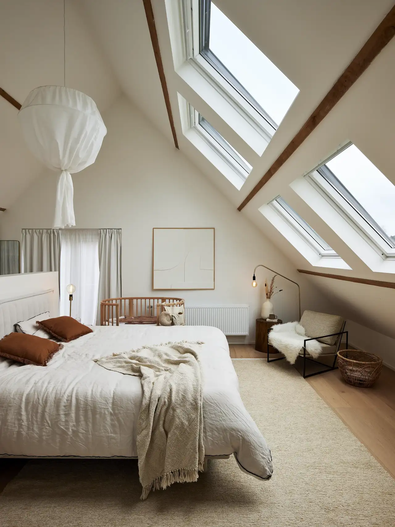 Camera da letto in mansarda con quattro grandi finestre per tetti e pavimento in legno