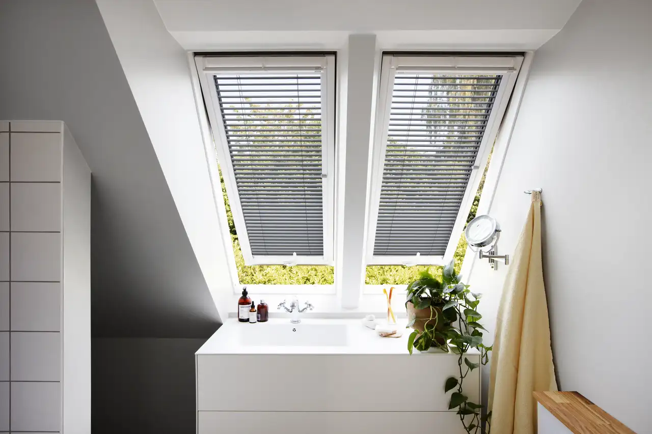 Kopalnica v mansardi z nagnjenim stropom in odprtimi strešnimi okni VELUX. 