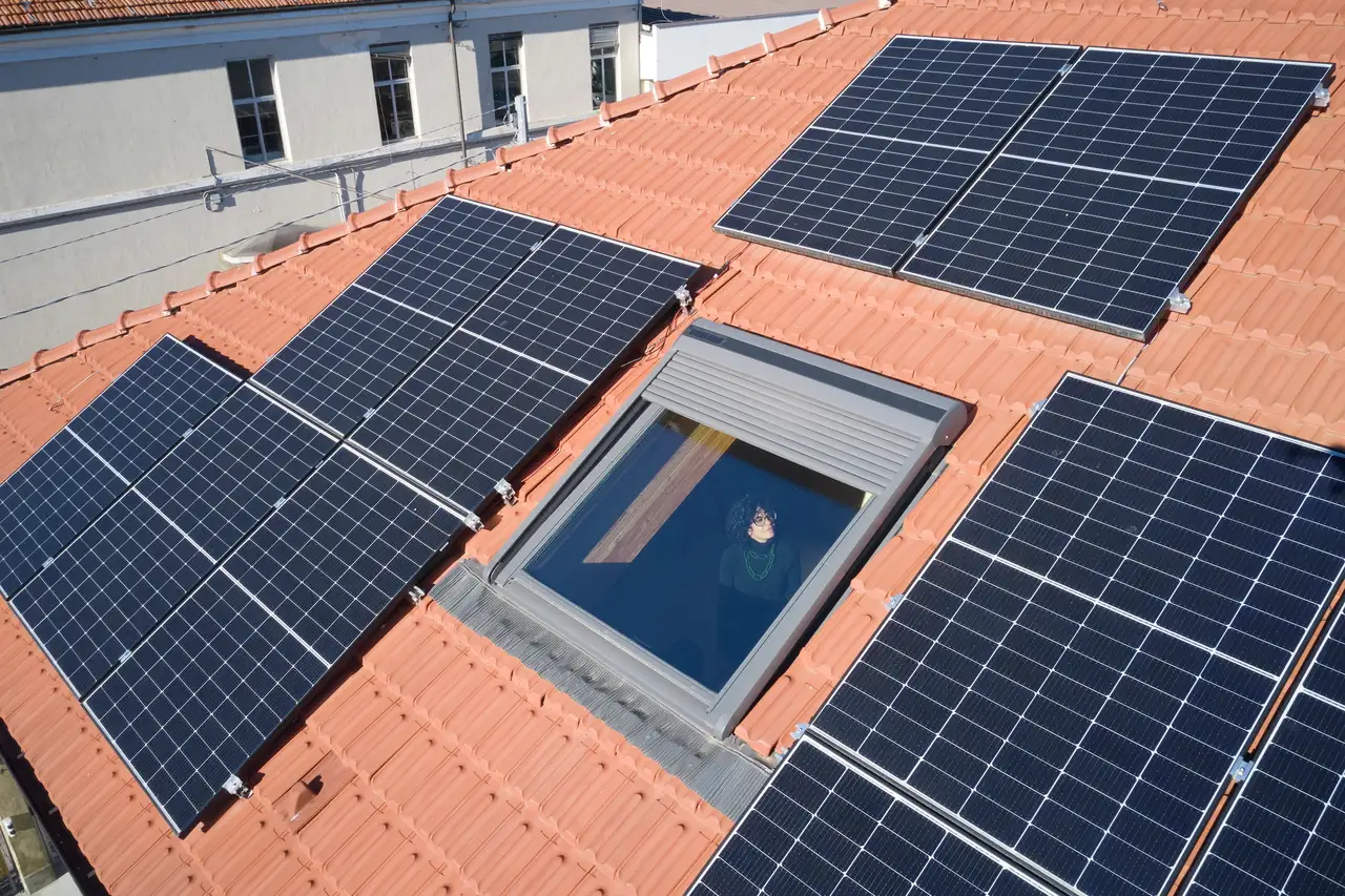 Ensemble de panneaux solaires installés sur un toit en pente. Plusieurs panneaux sont disposés en rangées, l'un d'entre eux étant incliné vers l'extérieur, éventuellement à des fins de maintenance ou de ventilation.