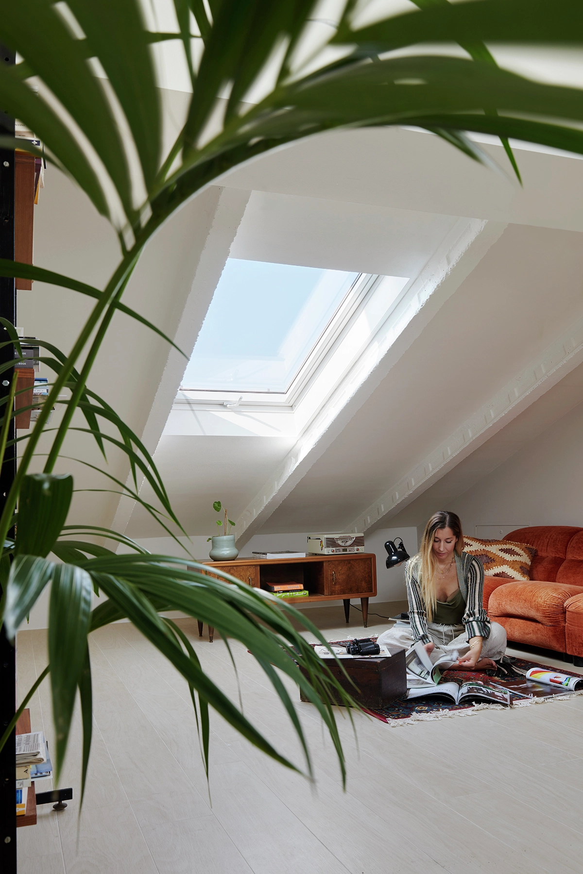 Bureau à domicile dans le comble avec fenêtre VELUX, bureau vintage et plante luxuriante.