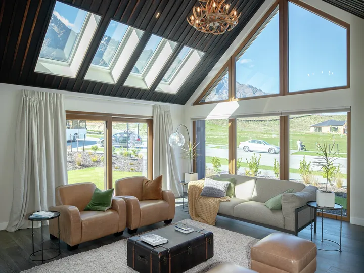 Sunny living room with VELUX roof windows and large gable glazing overlooking mountains.