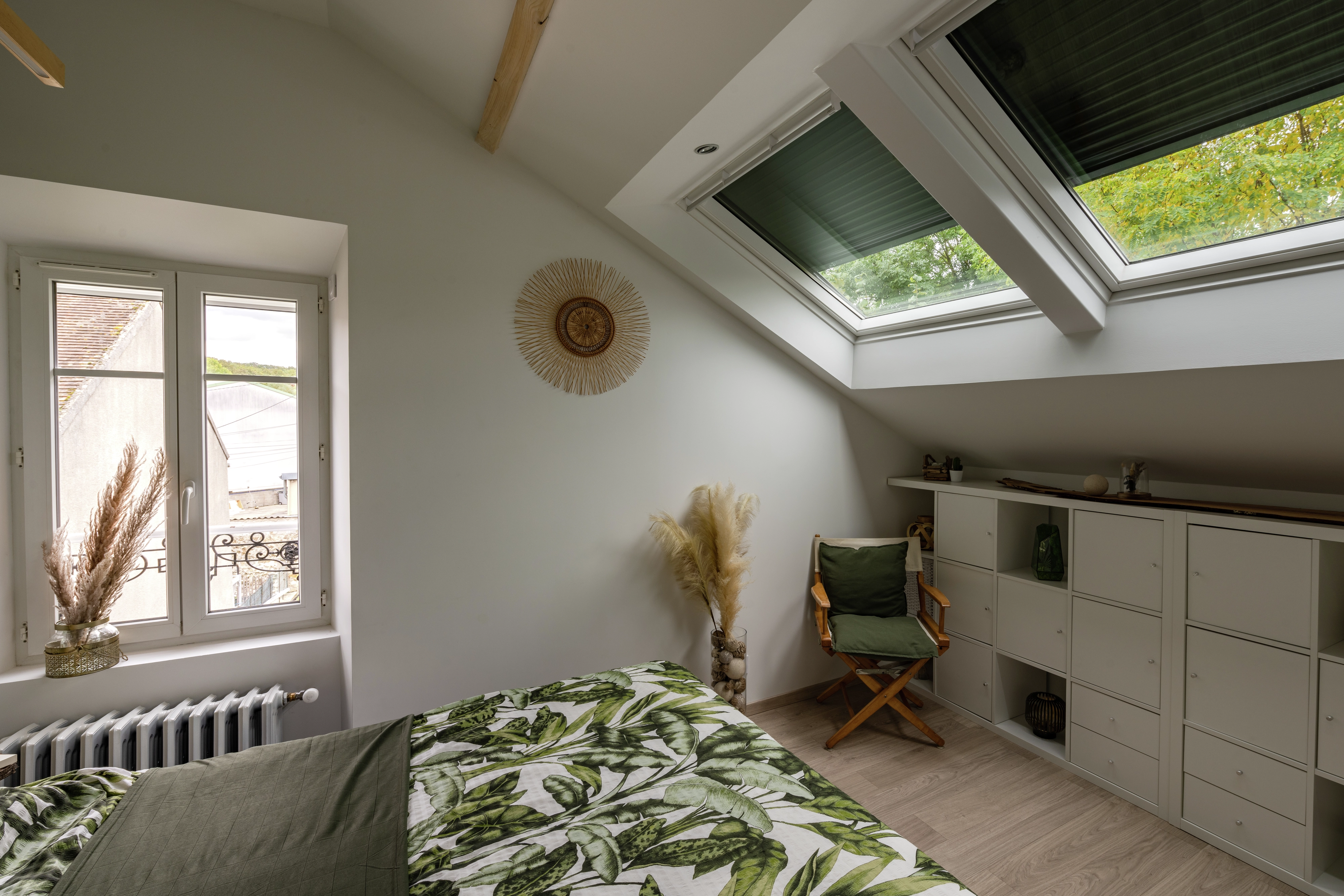 Attic bedroom with sloped ceiling and VELUX roof window, green decor.