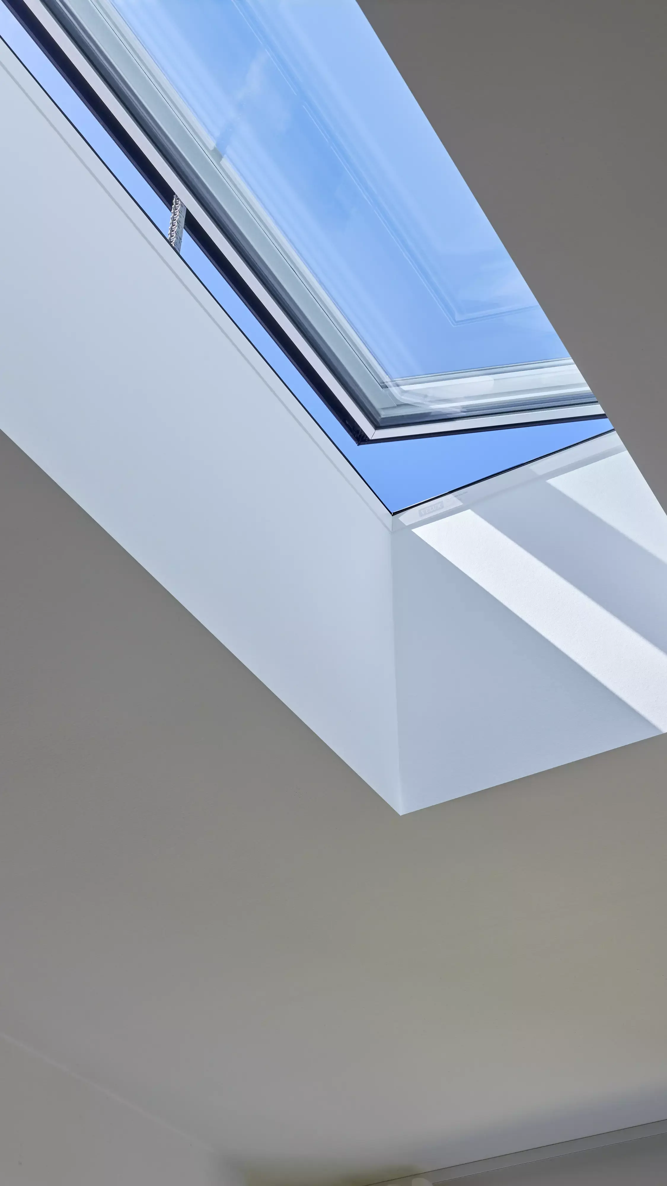 Fenêtre de toit VELUX dans une pièce minimaliste, inondant l'espace de lumière naturelle.