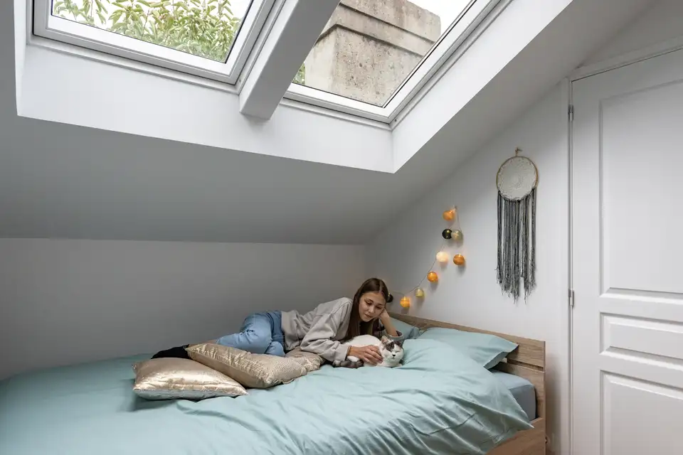 Chambre mansardée avec lit à la française, positionné côté long contre la pente basse du toit. 
