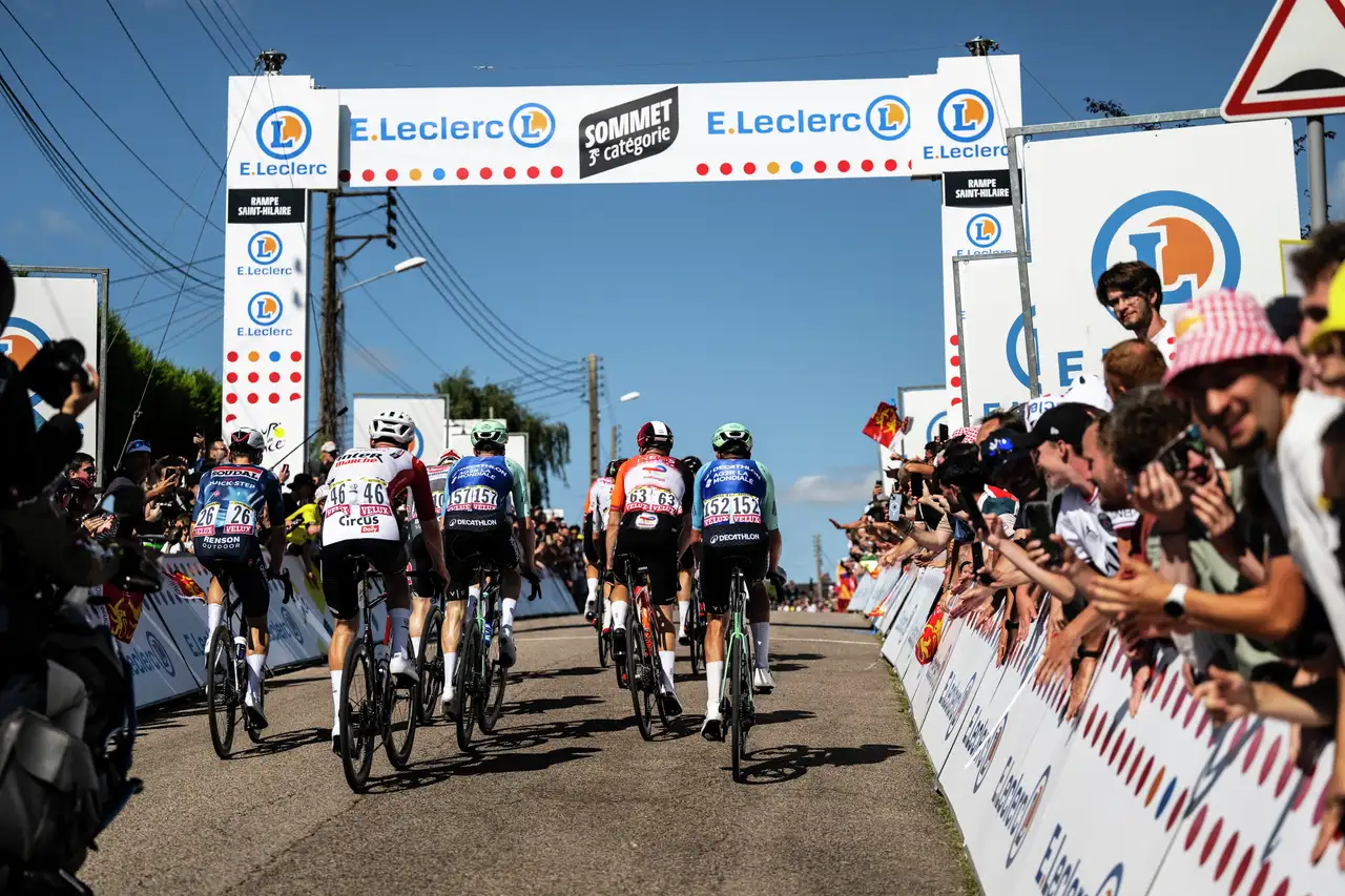 Kolesarji drvijo proti vrhu, gledalci Tour de France jih spodbujajo ob trasi.