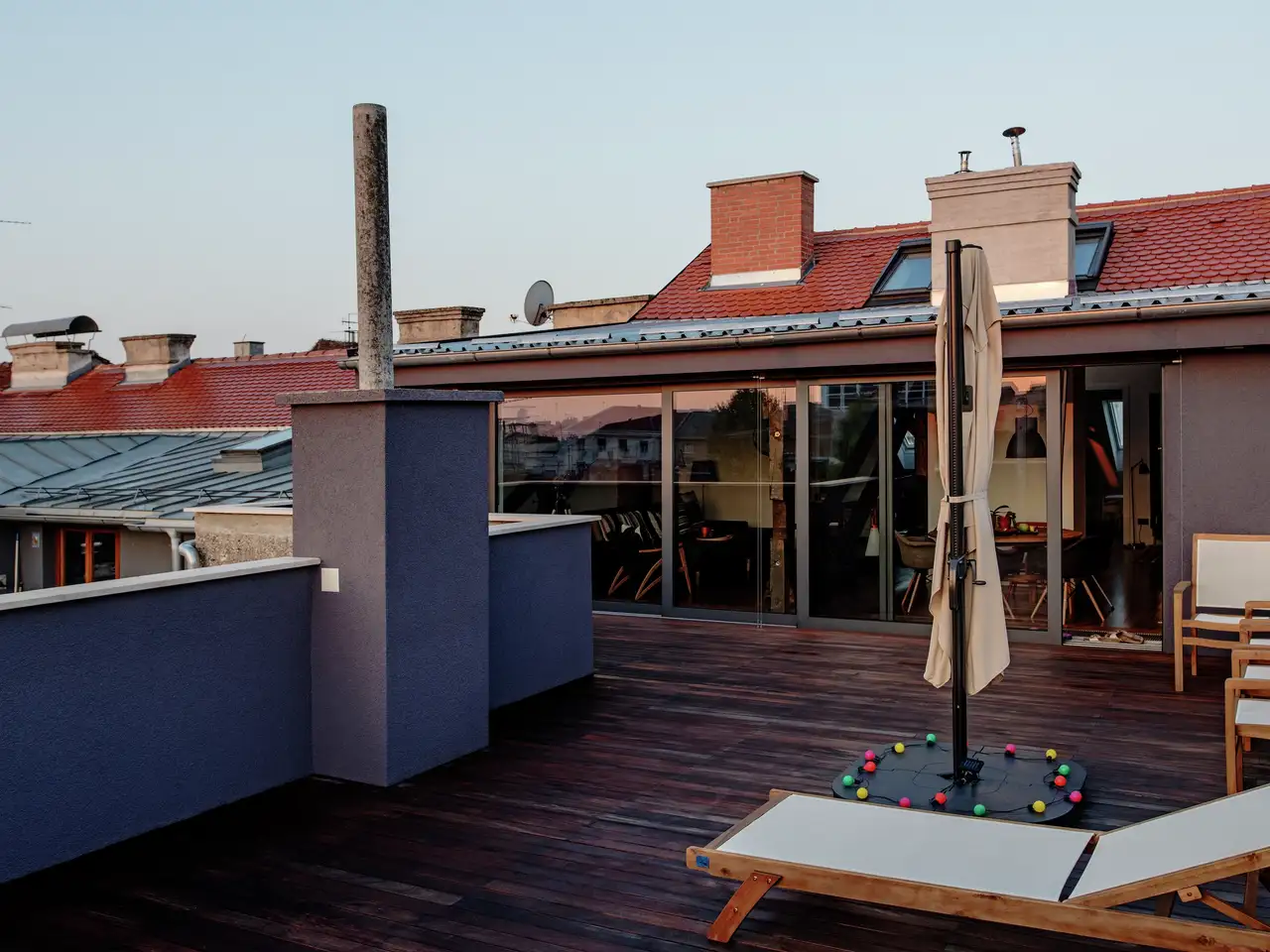 Terrazza a tetto piano alla luce della sera con sdraio e ombrellone | Rivista VELUX