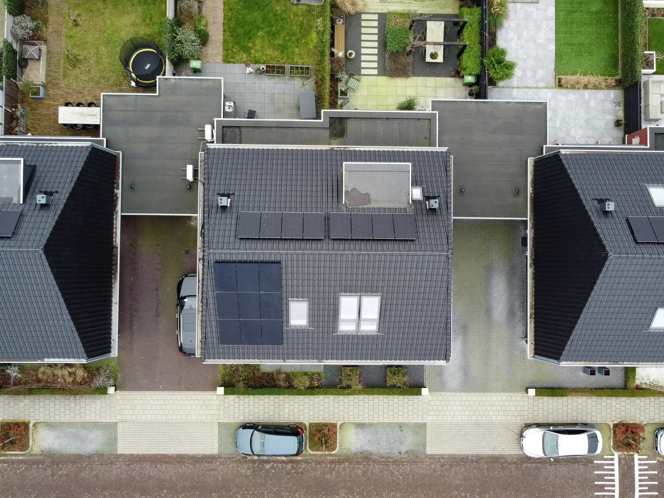 Vue aérienne d'un quartier résidentiel avec une fenêtre de toit VELUX sur un toit en tuiles sombres.